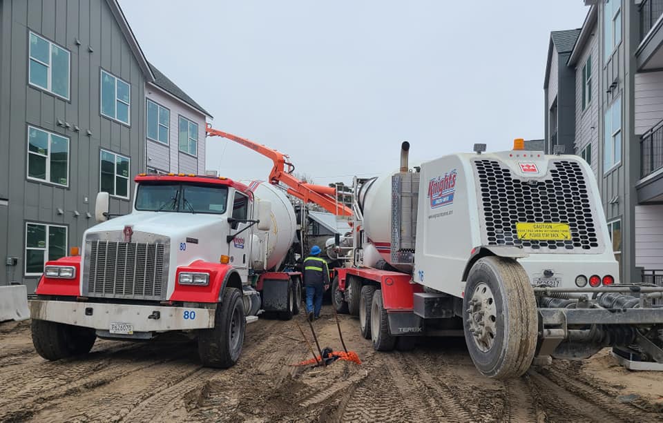 Mixer truck discharging in pump truck on a cold day.